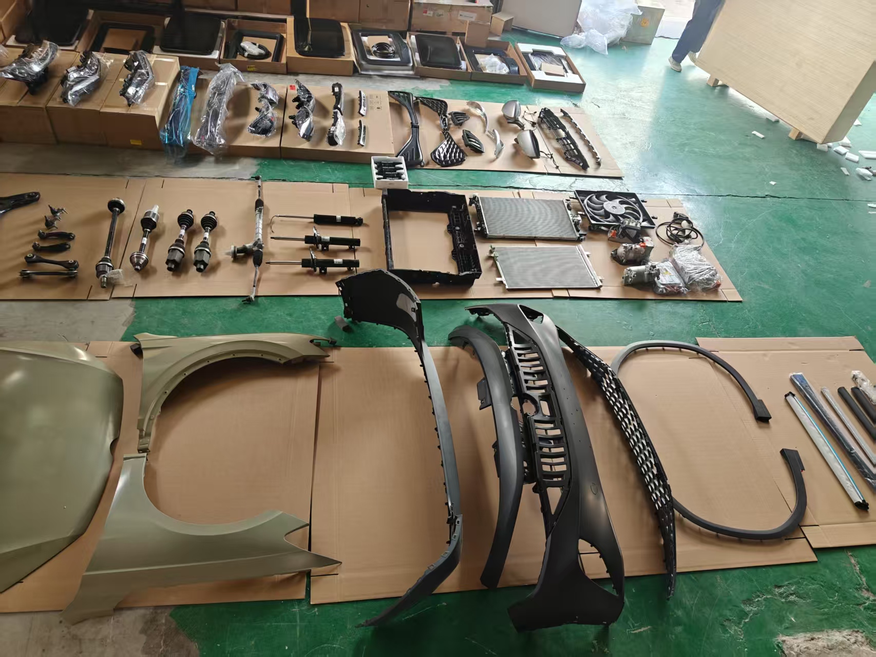 EV body panels, bumpers and drivetrain parts laid out for inspection